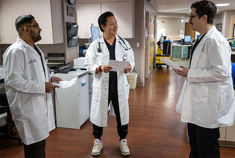 Parkview Medical Center doctors. Dr. Daniel Lee, center, did his internal medicine residency at Parkview Medical Center more than a decade ago and now runs the program. Dr. Amil Shah, left, and Dr. Dillin Rhatigan, right, talk with Lee in the hospital. Photo by Mike Sweeney, for UCHealth.