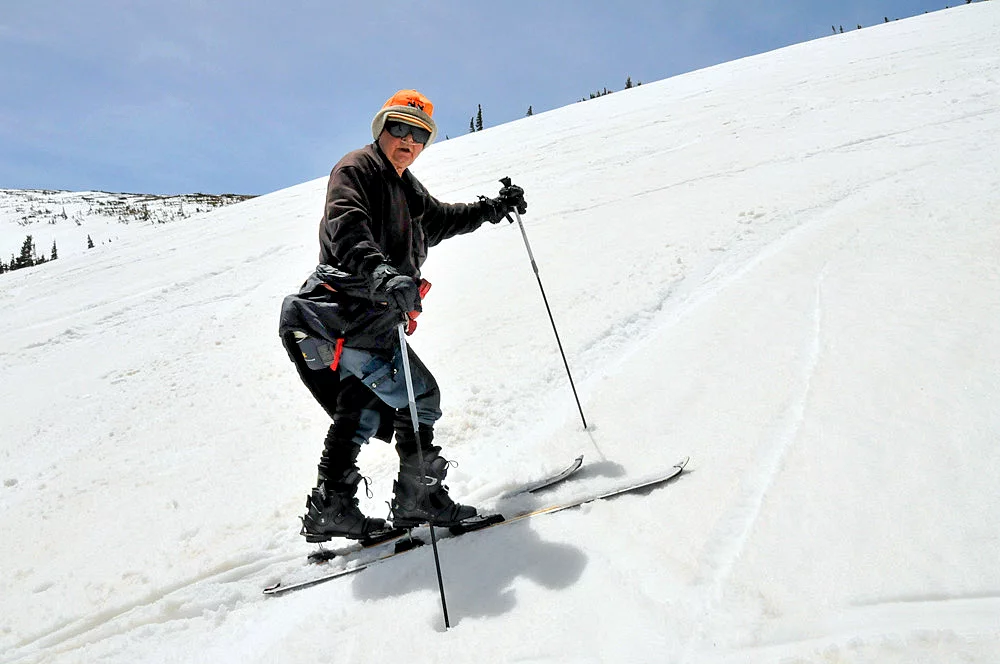 Duane "Shorty" Lankford skins on skis up a snowy mountain side.