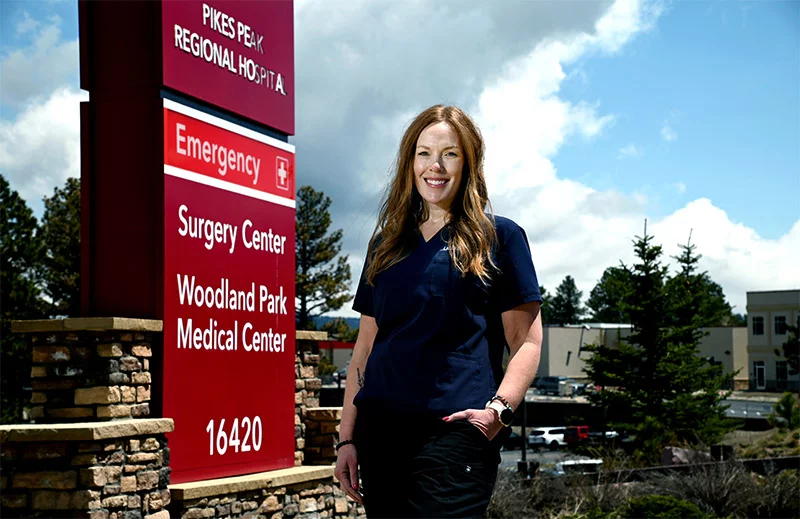 Nurse stands by sign outside the hospitalKaty Smith. Photo: Sonya Doctorian, UCHealth