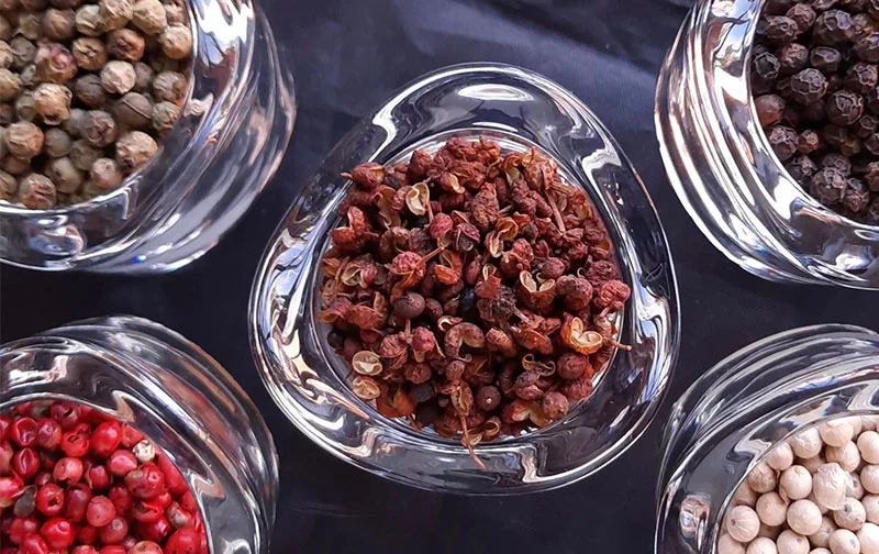 Clockwise from top left: Green peppercorns; Sichuan “peppercorns”; black, then white peppercorns; and red “peppercorns” (a seed from a member of the cashew family). Photo by Bill St. John for UCHealth.