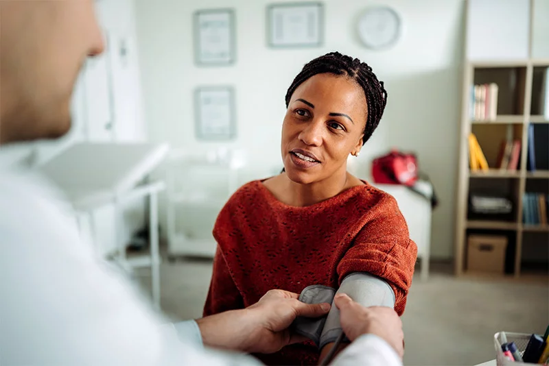 A woman getting her blood pressure taken by a doctor. New recommendations encourage earlier detection and treatment of high blood pressure, also called hypertension. Photo: Getty Images.