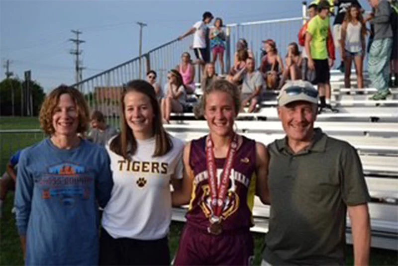 Chrissy Lofgren with family at state meet. Chrissy Lofgren, with medal, regularly qualified for high school state track competitions in Minnesota. She credits the support of her parents, Sue Lofgren, left, and Jim Lofgren, right, and her sister, Amy, for her running successes, including the Pikes Peak Marathon. Photo courtesy of Amy Lofgren.