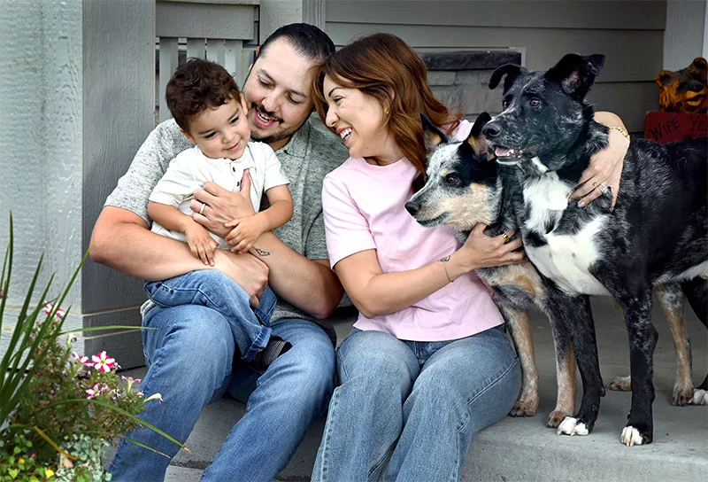 Jeremy Ortiz holds son, Baker, 2, while Kristine hugs the family dogs, Bear and Hank, on the front porch of their Thornton home. Jeremy is a sergeant with the Broomfield Police Department. “I’m totally supportive of whatever Kristine decides,” he said. “We’re just taking it step by step, each day at a time.” Photo by Sonya Doctorian, UCHealth.