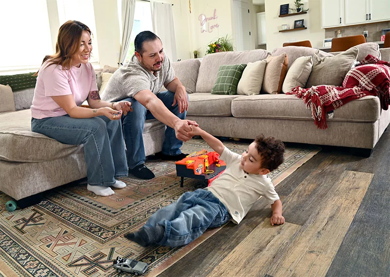 Kristine with her family in their living room. Jeremy helps Baker back to his feet after he was showing off for his parents. Photo by Sonya Doctorian, UCHealth.